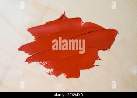 Ein Abstrich von roter Ölfarbe auf einem hölzernen Hintergrund. Layout für Ihr Design. Stockfoto