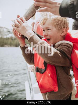 Junge auf einem Boot mit einem frisch gefangenen Fisch, USA Stockfoto