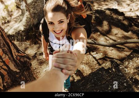 Nahaufnahme eines Mannes, der der Frau hilft, einen Felsen zu erklimmen. Frau klettert einen Felsen mit Hilfe eines männlichen Freundes. Stockfoto