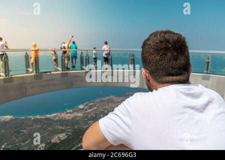 Mann, der am Eingang des Skywalk steht, der über den berg biokovo führt und in die Ferne blickt. Die Leute sahen, wie sie über die Glaskonstruktion gingen Stockfoto