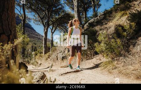 Frau, die auf einem Bergweg geht. Weibchen auf Wandertour mit Blick auf den Berg. Stockfoto