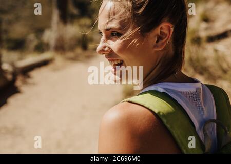 Nahaufnahme einer lächelnden Wanderin auf dem Bergweg. Frau, die einen Berg wandert und glücklich aussieht. Stockfoto