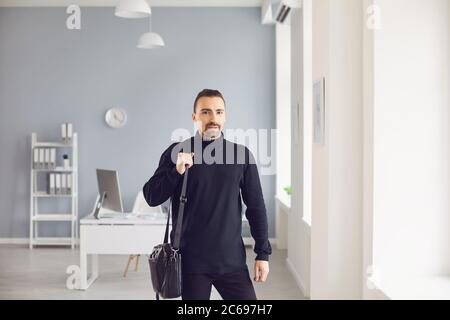 Moderner Mann mit Laptoptasche im hellen Büro Stockfoto