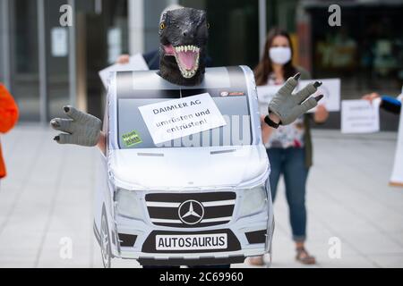 Stuttgart, Deutschland. Juli 2020. Vor dem Mercedes-Benz Global Training Center in Stuttgart-Vaihingen steht ein Demonstrator in einem SUV-Kostüm mit Dinosaurierkopf. Zusammen mit anderen Demonstranten fordert er eine sozial-ökologische Umstrukturierung des Automobilkonzerns und eine Exportstopp für Militärfahrzeuge. Aufgrund der Corona-Pandemie findet die Hauptversammlung des Automobilherstellers Daimler derzeit später als geplant und nur online statt. Quelle: Tom Weller/dpa/Alamy Live News Stockfoto