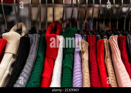 An Kleiderbügeln hängen Nahaufhängungen. Im Ladenstand, Verkauf. Helle Farbpalette. Stockfoto