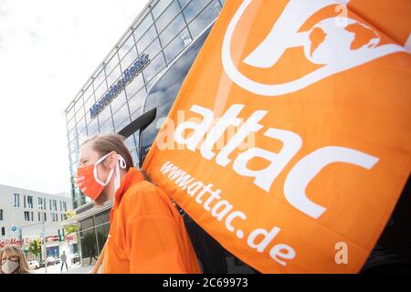 Stuttgart, Deutschland. Juli 2020. Ein Demonstrator hält eine Fahne mit der Aufschrift "attac" in der Hand und steht vor dem Mercedes-Benz Global Training Center in Stuttgart-Vaihingen. Er fordert eine sozial-ökologische Umstrukturierung des Automobilkonzerns und eine Exportstopp für Militärfahrzeuge. Aufgrund der Corona-Pandemie findet die Hauptversammlung des Automobilherstellers Daimler derzeit später als geplant und nur online statt. Quelle: Tom Weller/dpa/Alamy Live News Stockfoto