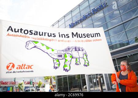 Stuttgart, Deutschland. Juli 2020. Demonstranten heben ein Banner mit der Aufschrift 'Autosaurus ins Museum'. Sie fordern eine sozial-ökologische Umstrukturierung des Automobilkonzerns und eine Exportstopp für Militärfahrzeuge. Aufgrund der Corona-Pandemie findet die Hauptversammlung des Automobilherstellers Daimler derzeit später als geplant und nur online statt. Quelle: Tom Weller/dpa/Alamy Live News Stockfoto