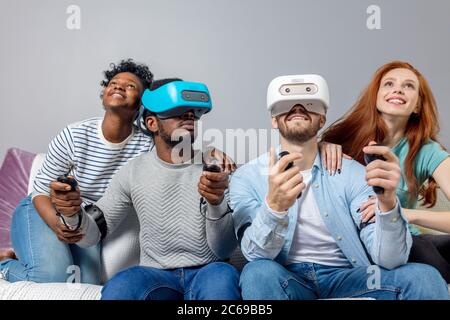 Zwei multirassischen junge Paare Spaß beim Besuch Entertainment Center in Wochenende. Emotionale Jungs in VR-Headsets Erfahrung Freude und Aufregung w Stockfoto