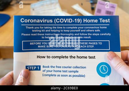 Coronavirus (Covid-19) Anweisungen, die einem Testkit für die Durchführung eines Heimtests beiliegen, der von den Händen eines Mannes gehalten und gelesen wird, Großbritannien Stockfoto