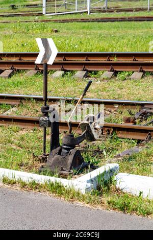 Vintage manuelle Übersetzer von Eisenbahn Pfeile. Der Mechanismus der Eisenbahn Schalter auf dem Hintergrund der Gleise und grünes Gras an einem sonnigen Tag. Stockfoto