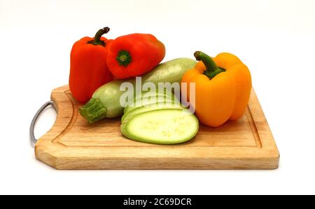 Zucchini und reifer Paprika in verschiedenen Farben auf einem Schneidebrett auf einem hellen Hintergrund. Naturprodukt. Natürliche Farbe. Nahaufnahme Stockfoto