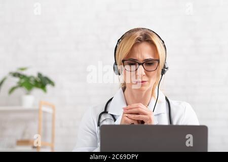 Beschwerden beim Arzt. Attraktive Erwachsene Frau mit Kopfhörer konzentriert hört Patienten Stockfoto