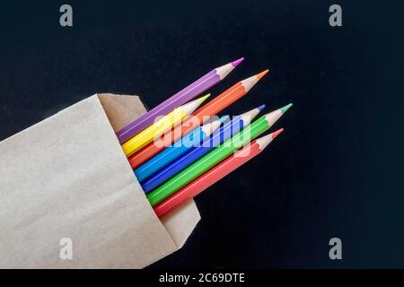 Mehrfarbige Bleistifte in einer Basteltasche auf schwarzem Hintergrund Stockfoto