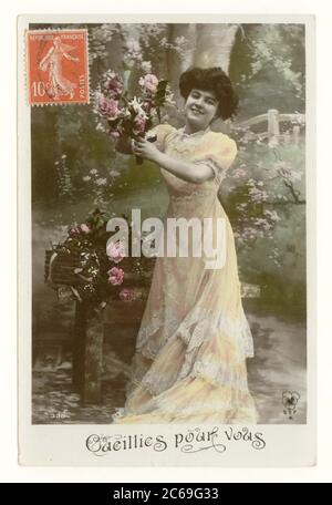 Anfang des 20. Jahrhunderts französische sentimental getönte Grußkarte einer hübschen Frau in einem langen, fließenden Kleid, lächelnd und Rosen pflücken - mit dem Titel 'für Sie gepflückt', Frankreich, um 1911 Stockfoto