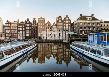 AMSTERDAM, NIEDERLANDE - 16. FEBRUAR 2016: Alte Gebäude am Damrak in Amsterdam tagsüber. Boote können gesehen werden. Stockfoto