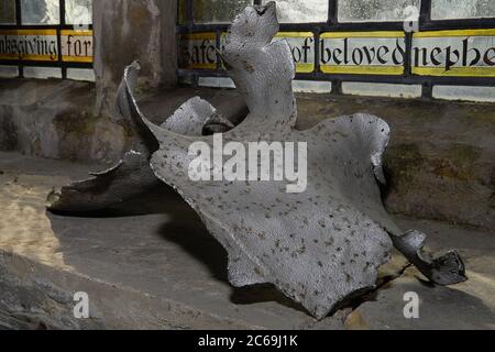 Verdrehter Scherbenhaufen aus Metallsplittern, der jetzt auf der Fensterbank in der Pfarrkirche Saint Laurence in Hawkhurst, Kent, England, UK, ausgestellt ist, ist der Rest der deutschen V1-Flugbombe, die im August 1944 während des Zweiten Weltkriegs auf dem Kirchhof explodierte. Viel altes Buntglas ausblasen und weitere Schäden verursachen. Obwohl die Kirche bis 1957 nicht vollständig repariert wurde, wurden später Teile des zerbrochenen Glases zu einem neuen Rundel gemacht und es profitierte auch von Schenkungen aus altem Glas von anderswo. Stockfoto