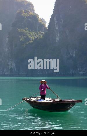 Eine Vietnamesin mit Reismütze rudert ein Bambusboot im Fischerdorf Vung Vieng in der Ha Long Bay, Vietnam Stockfoto