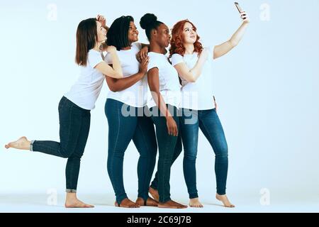 Studenten der Universität machen Selfie im Studio in Skinny Jeans und weißen T-Shitrs. Alle Frauen sind natürlich und unterschiedlich in ihrer gemeinsamen Schönheit, hav Stockfoto