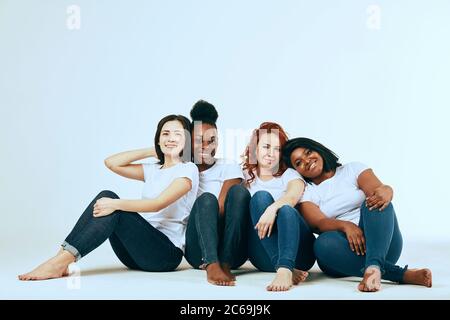 Studenten posieren im Studio in Skinny Jeans und weißen T-Shitrs. Alle Frauen sind natürlich und unterschiedlich in ihrer gemeinsamen Schönheit, mit verschiedenen sk Stockfoto