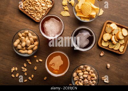 Kundenservice im Pub. Dunkles, helles, ungefiltertes Bier in Gläsern, Nüsse und Chips in Tellern Stockfoto