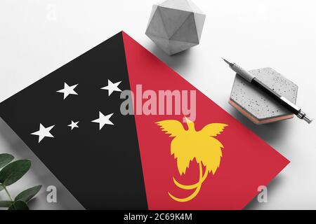 Papua-Neuguinea-Flagge auf minimalistischem Papierhintergrund. Nationale Einladung Brief mit stilvollen Stift auf Stein. Kommunikationskonzept. Stockfoto