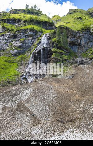 Schmelzwasser fließt ab und fällt die Klippe hinunter auf einen Lawinenabbruchkegel, Österreich, Kärnten, Nationalpark hohe Tauern Stockfoto