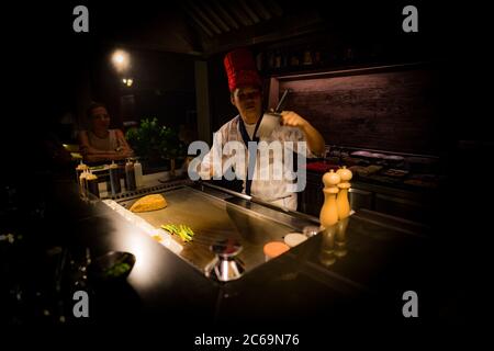 Mai, 2018 - Ari Atoll, Malediven: Fröhlicher Teppanyaki-Koch kocht Gemüse-Teppan im japanischen Steakhouse auf Mishi Sushi. Gourmet-Essen, Luxus-Restaurant Stockfoto