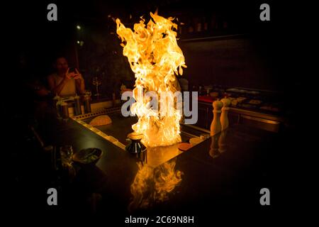 Mai, 2018 - Ari Atoll, Malediven: Fröhlicher Teppanyaki-Koch kocht Gemüse-Teppan im japanischen Steakhouse auf Mishi Sushi. Gourmet-Essen, Luxus-Restaurant Stockfoto