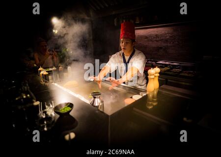 Mai, 2018 - Ari Atoll, Malediven: Fröhlicher Teppanyaki-Koch kocht Gemüse-Teppan im japanischen Steakhouse auf Mishi Sushi. Gourmet-Essen, Luxus-Restaurant Stockfoto