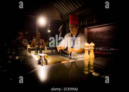 Mai, 2018 - Ari Atoll, Malediven: Fröhlicher Teppanyaki-Koch kocht Gemüse-Teppan im japanischen Steakhouse auf Mishi Sushi. Gourmet-Essen, Luxus-Restaurant Stockfoto