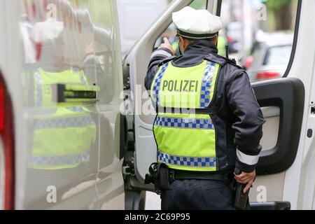 24. April 2020, Hamburg: Ein Polizist ist bei einer Polizeikontrolle in der Max-Brauer-Allee im Einsatz. Er hält seine Hand an seiner Dienstwaffe. Die Hamburger Polizei hat die Fahrer im Landkreis Altona auf die Einhaltung des Dieselfahrverbots überprüft. Auf fast 600 Metern der Max-Brauer-Allee gibt es ein Fahrverbot für ältere Diesel- und Lkw. Verstöße werden mit Geldbußen belegt. Foto: Bodo Marks/dpa Stockfoto