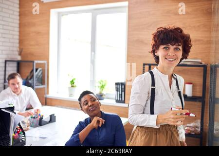 Junge kaukasische Frau schreibt auf Flipchart zeigt ihr Upgrade in Unternehmen, Schemata Stockfoto