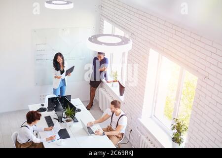 Draufsicht auf internationales Business-Team lachen zusammen im Büro. Weiß innen. Ruhe nach der Arbeit Stockfoto