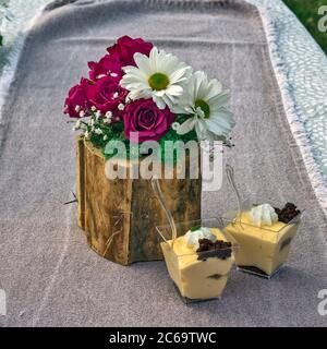 Blumen und Pudding als Dekoration auf den Tisch gelegt. Der Pudding wird für Verkostung und Bewertung vorbereitet, sowie eine Blumenarrangement. Stockfoto