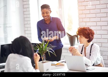 Lächelnder afrikanischer Business Coach, der mit Flipchart über Arbeitsergebnisse berichtet und kaukasiern neue Projektidee erklärt. Stockfoto