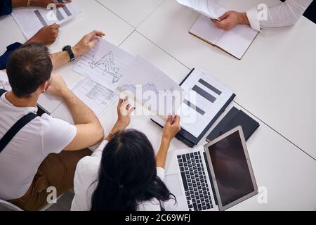 Mit Laptops bei der Arbeit, Geschäftsleute sitzen auf dem Tisch über Strategie, eine Menge Papiere auf dem Tisch, Finanzen Stockfoto