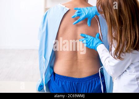 Junger verletzter Mann, der einen weiblichen Arzt aufsucht, Chiropraktiker Stockfoto