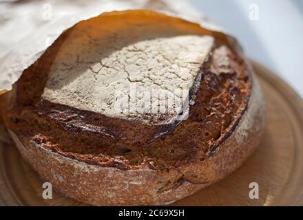 Ein Laib Roggensauerteig in einem Papierbeutel auf einem Brotbrett Stockfoto