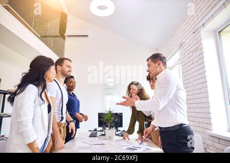 Junge kaukasischen Mann in weißen formellen Hemd Stand erklärt Kollegen neue Geschäftsidee, isoliert in weißem Büro Stockfoto