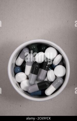 Farbige Tabletten und Kapseln werden aus der Verpackung entfernt. Farbige Tabletten und Kapseln von oben oder im Behälter. Stockfoto