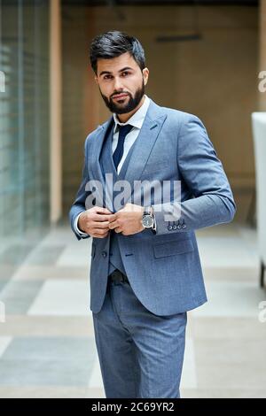 Elegante männliche in Anzug posiert in der Straße. Attraktive Brünette in grauem Anzug, schwarz behaart Stockfoto