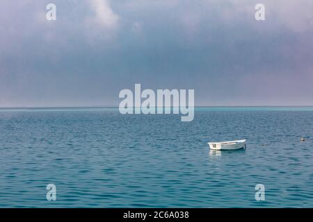Altes Ruderboot auf See. Einsames Holzboot, wolkig Himmel, ruhiges Meer Wellen mit Horizont. Stockfoto