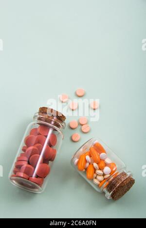 Pillen und farbige Kapseln außerhalb der Verpackung im Glasbehälter in der Verpackung. Stockfoto