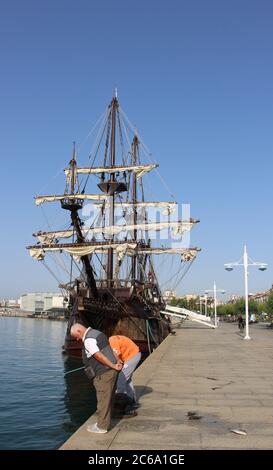 Angeln vor der Nachbildung des Victoria-Schiffes eine Karacke und das erste Schiff, das den Globus umrundet, vor Anker in Santander mit starkem Sonnenlicht Stockfoto