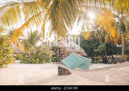 Landschaftsansicht des Sonnenuntergangs, leere Hängematte auf Kokospalmen auf einer tropischen Insel. Sommer-Vibes, Stimmung, Erholung, Entspannung Stockfoto