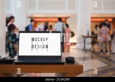 Mockup leerer weißer Bildschirm Laptop mit verschwommenen Menschen warten auf Registrierung in der Hotelhalle Stockfoto