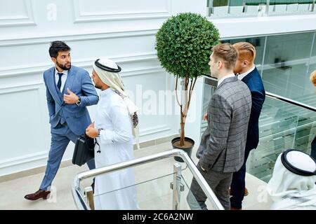 Kaukasischer Mann in Smoking und scheich gehen die Treppe hinauf und sprechen, diskutieren zukünftige Geschäftsideen Stockfoto
