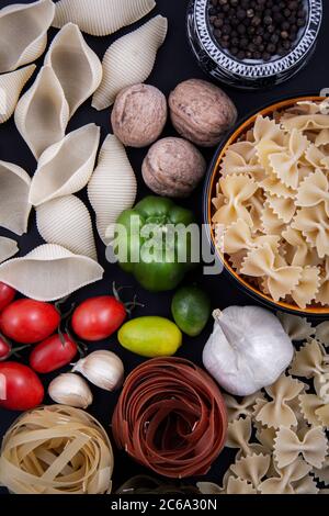 Bunte und bunte Pasta in großer Zahl und in verschiedenen Farben zusammen mit verschiedenen Früchten und Gemüse. Stockfoto