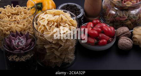 Bunte und bunte Pasta in großer Zahl und in verschiedenen Farben zusammen mit verschiedenen Früchten und Gemüse. Stockfoto