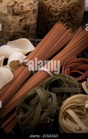 Pasta in Form und Pasta in Form. Pasta in verschiedenen Formen und Farben mit einer Vielzahl von Früchten und Holzgerichten. Stockfoto